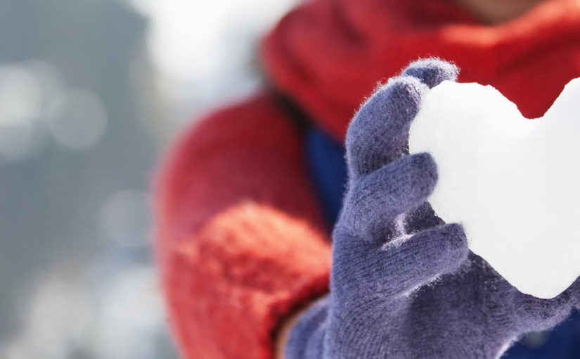 Portrait of smiling woman holding heart-shape snowball