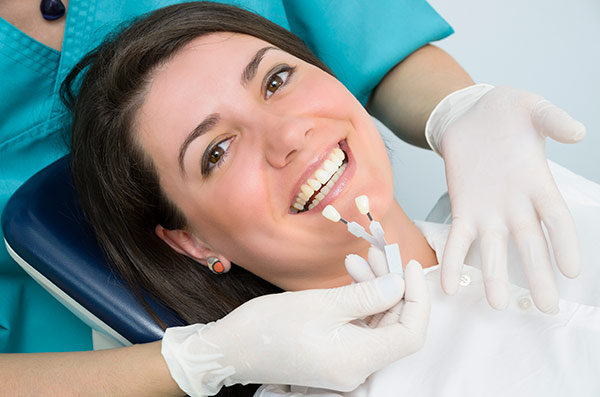 Smiling woman in dentist’s chair looking at dental implant options