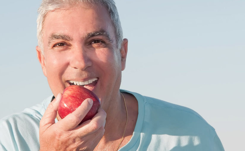 Senior male with dentures biting apple